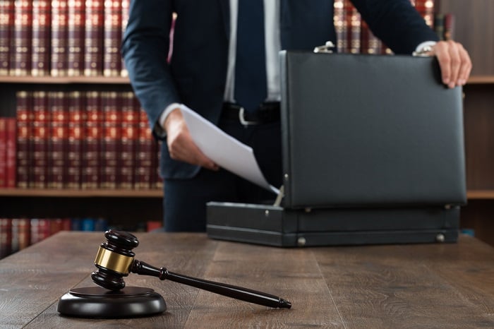 Image of man with briefcase in front of law books.