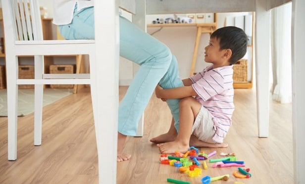 Woman sitting with child grabbing her leg