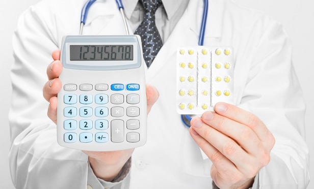 Doctor holding up package of pills and caculator