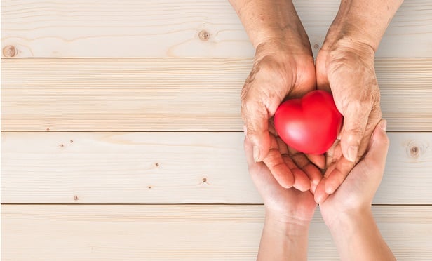 Two sets of hands holding a heart