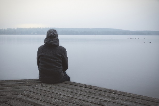 man sitting alone at a lake
