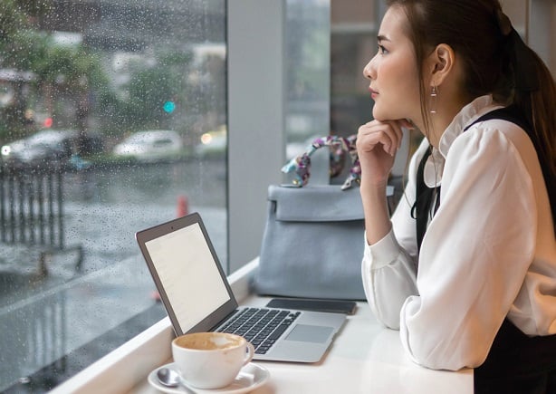 woman at rainy window with laptop