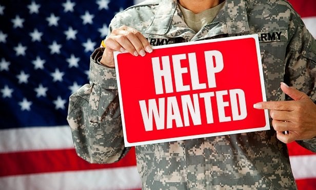 Military person holding help wanted sign