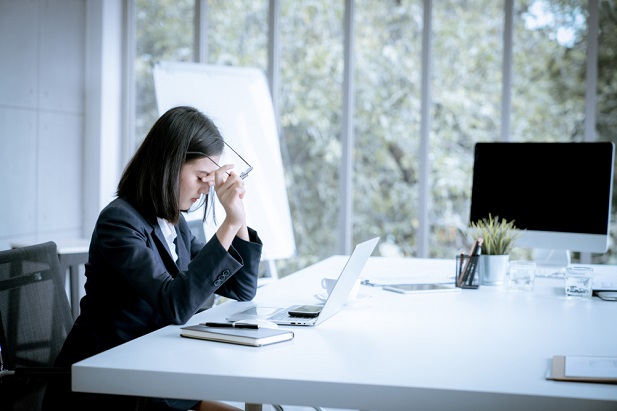 woman rubbing forehead while at computer