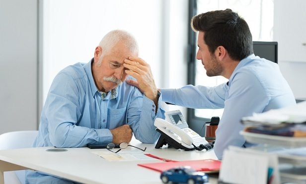 Younger worker consoling older worker