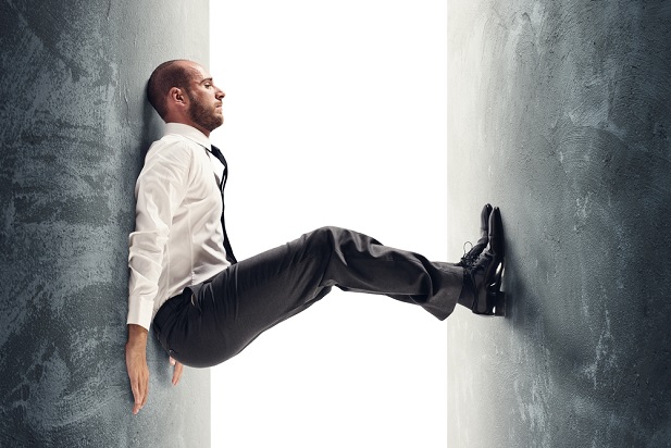 man in tie trying to balance between two walls