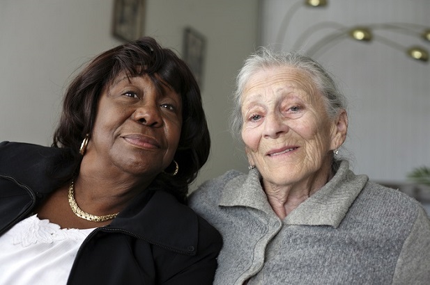 two older women, one black, one white, smiling pensively