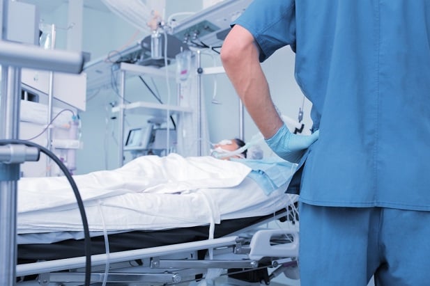 nurse standing by patient in hospital bed