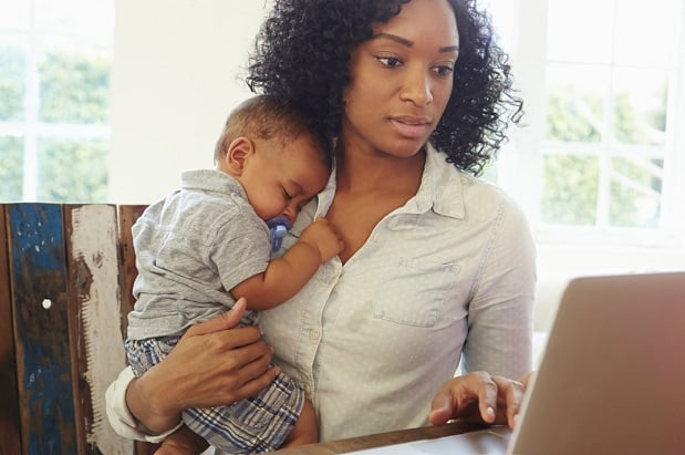 young mother with infant trying to check screen of her laptop