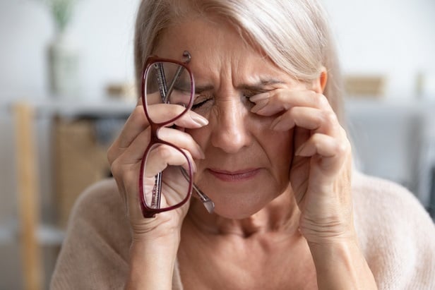 stressed older woman rubbing eyes.