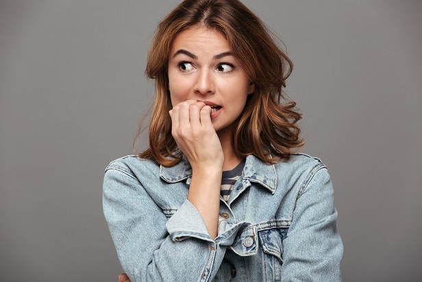 woman with hands to mouth looking stressed