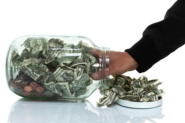 Man pulling cash out of a jar.