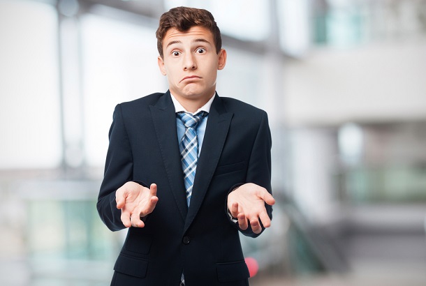 young man in business suit with hands up in helpless and confused gesture