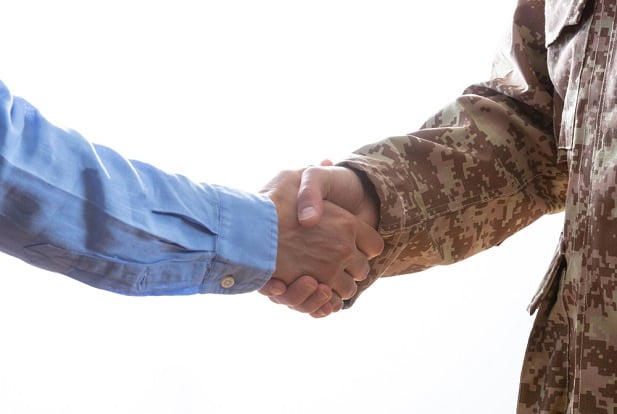 closeup of business man and soldier in camo shaking hands