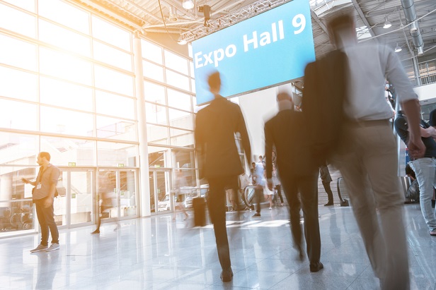 blurred photo of people walking toward an expo hall at a trade show