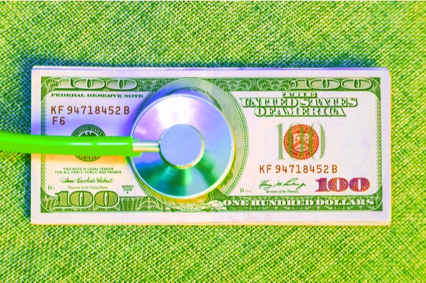 green stethoscope on top of 100 dollar bill on green background