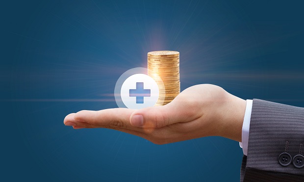Hand holding coins and health care symbol