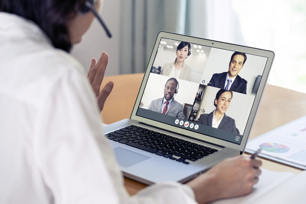 woman wearing headset in meeting with 4 business men and women online