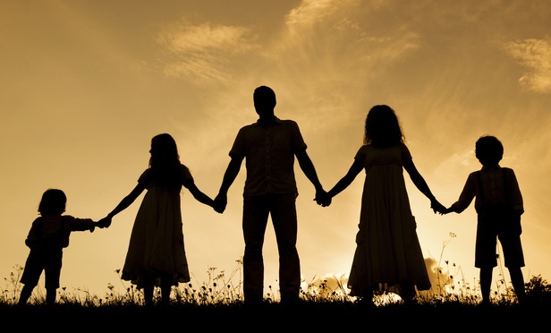 silhouette of five person family holding hands on a hill