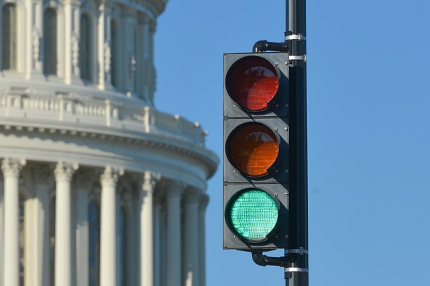 Closeup of Washington DC capitol building with green traffic light signal in foreground