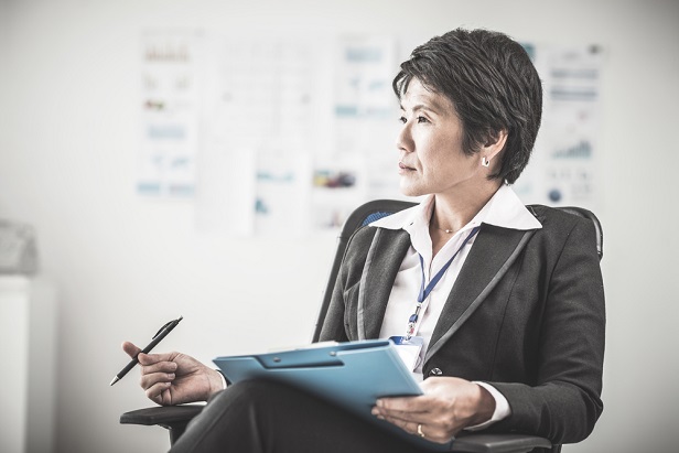 woman in business attire sitting with a clipboard and pen