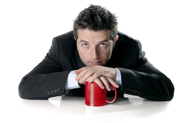 Business man leaning on a mug looking unmotivated