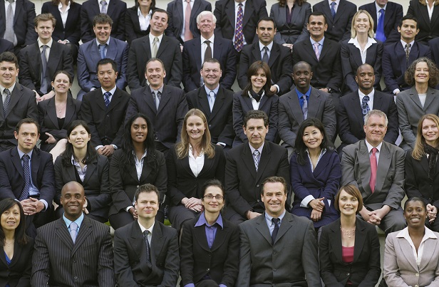 rows and rows of smiling men and women in black or dark business suits as if in a group photo shoot