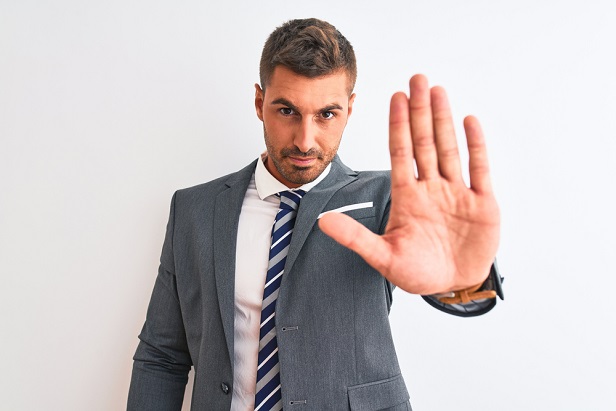 business man holding up hand with palm facing out in gesture of halt or rejection