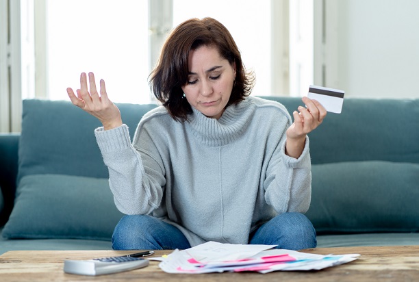 woman sitting on couch with bills and credit card looking fed up