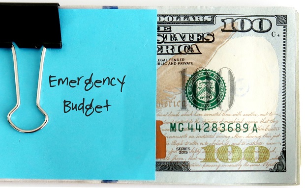 100 dollar bill with blue stickie note saying Emergency Budget clipped to it