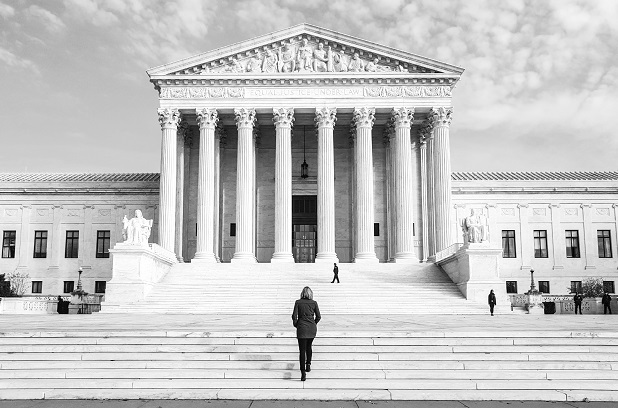 black and white photo of the U.S. Supreme Court building with a lone person in front