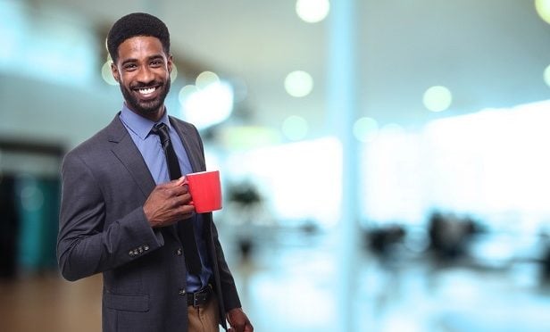 Man in business suit with coffee mug smiling