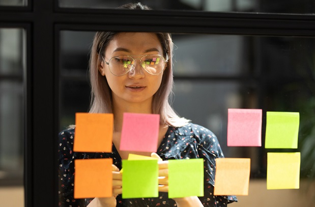 woman looking at stickie notes placed on window in office