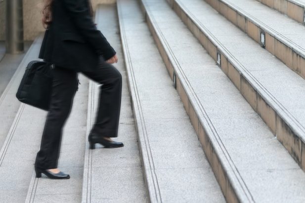business woman seen from waist down walking up stairs carrying briefcase