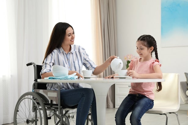 woman in wheelchair sitting at table with little girl