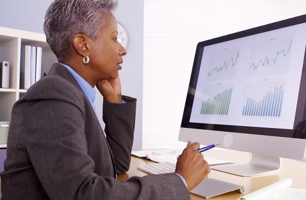 older business woman sitting at computer looking at chart
