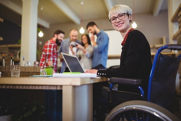 woman in wheelchair with office colleagues in background