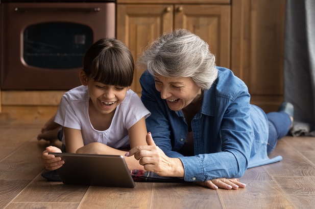 older woman using tablet with young girl