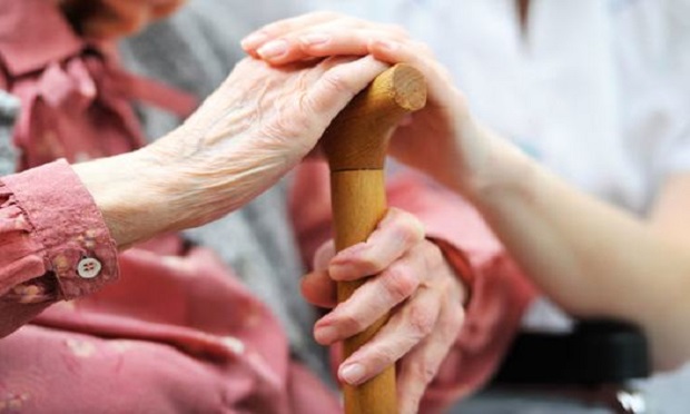 closeup of elderly hand on cane and younger hand on top