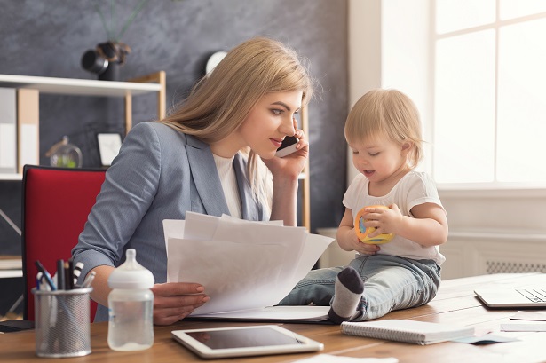 woman in business suit talking on phone and looking at child sitting on her desk