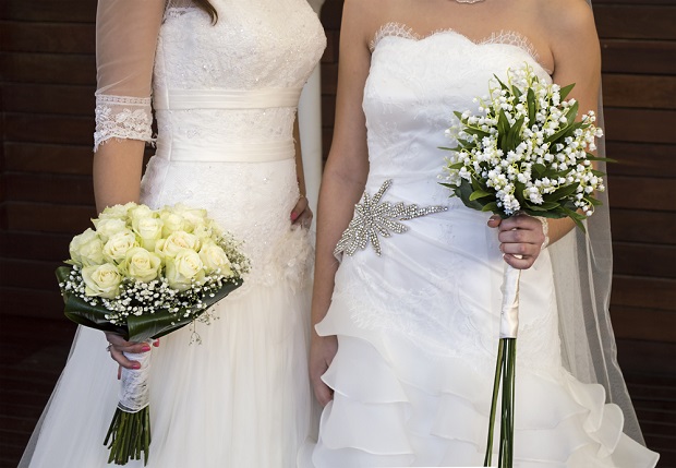 two women standing together in wedding gowns