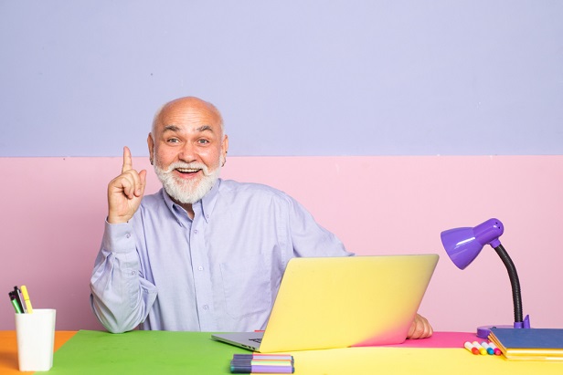 older man at laptop smiling