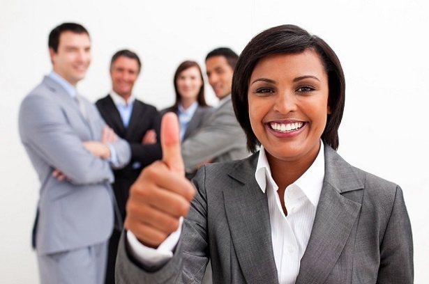 woman with thumb's up gesture with smiling colleagues