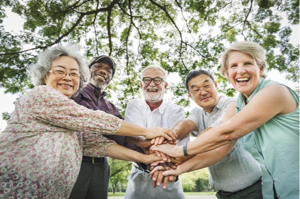 group of older people smiling and joining hands