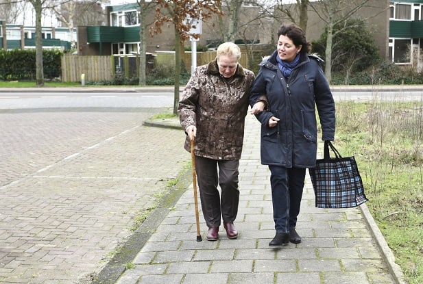 younger woman assisting older woman to walk