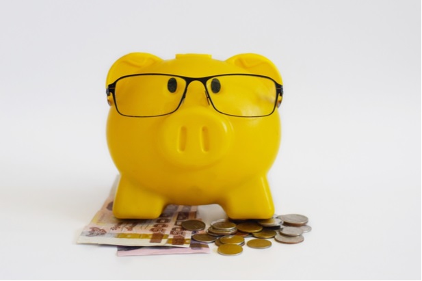 yellow piggy bank with eyeglasses on top of coins