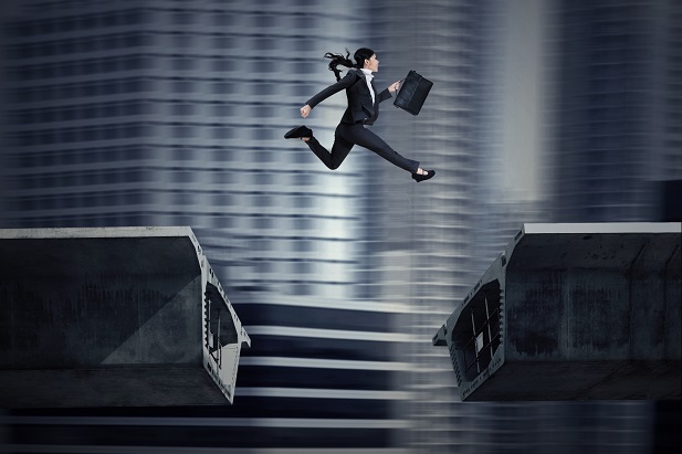 business woman with briefcase jumping across gap in steel beams