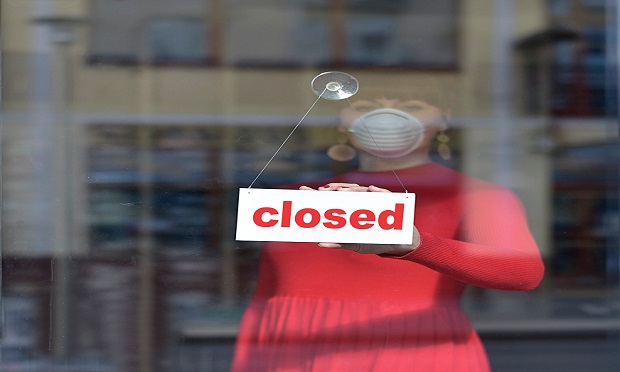 woman adjusting Closed sign in store window