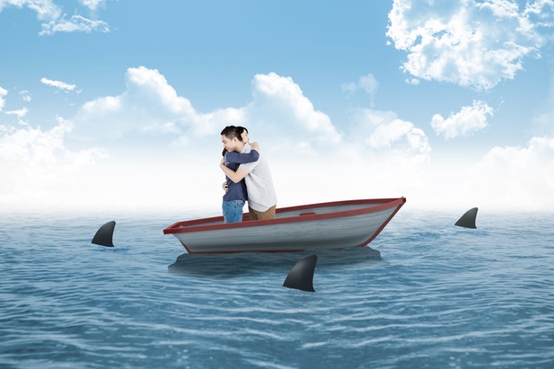 man and woman hugging in small boat as sharks circle
