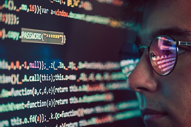 computer code reflected in man's eyeglasses